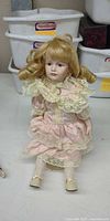 Full view of porcelain collector doll standing on stand