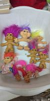 Full group of troll dolls in tub showing size range and hair colours