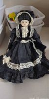 Full view of porcelain head cloth body doll in polka-dot dress and bonnet