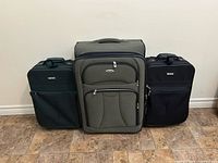 Front view of three softside rolling suitcases (WestJet center, Jaguar left and right) showing overall condition and sizes.