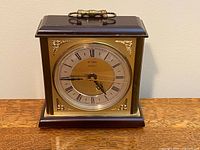 Front view showing dial, Roman numerals, wood case, handle