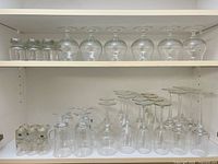 Shelf with six Kosta shot glasses and eight larger goblets