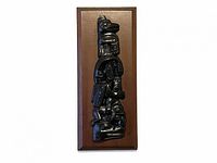 Full front view of vertical black resin totem plaque on wooden board