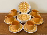 Full 18-piece Maidstone set: six cups, six snack plates, six larger plates displayed on wooden surface