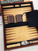 Open wooden backgammon case showing playing surface, dice cups, pouch and accessory compartments