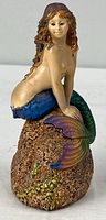Front view of painted cast plaster mermaid figurine on rock base