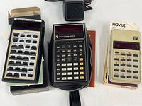 Three calculators, adapter and boxes overview