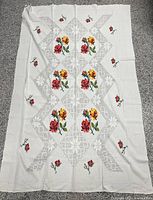 Full view of white cross-stitch rose tablecloth laid flat