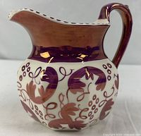 Full view of pitcher showing shape, purple lustre band and motif