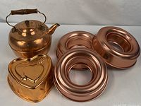Group shot of copper kettle, heart mold, three ring molds