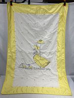 full view of yellow-bordered crib blanket with duck design