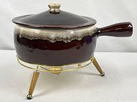 Casserole with lid on warming stand, side view