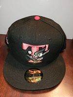 Front view of black fitted cap showing embroidered red T with pigeon graphic and 59FIFTY size sticker