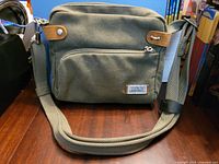 Front view of grey Travelon crossbody bag with strap and front pocket