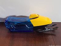 Left side view of blue glass snowmobile bottle with yellow cab and black skis