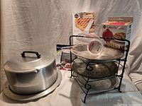 Group shot of cake carrier, pie plates, rack, packaged lattice tools, dough blender, measuring cup