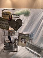 Entire lot showing steel rack loaded with accessories, signs, pouf, crocheted covers, shower curtain packages