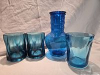 Set of translucent blue acrylic drinkware showing three tumblers and one bedside carafe