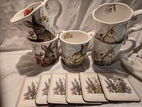 Group shot of five Maxcera bunny motif mugs stacked and displayed with six herb illustration coasters