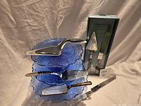 Full lot showing stacked blue plates, boxed Cambridge set, various servers and cutter