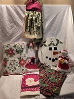 All items arranged: vinyl tablecloths, handmade holly tablecloth, towel & bag holder, Santa towel, snowman plaque, lighted Santa topper