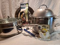 All cookware pieces and packaged utensils grouped together on neutral background