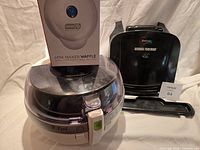 All three appliances grouped: boxed Dash Mini Waffle Maker on top of T-Fal Actifry, George Foreman grill beside it