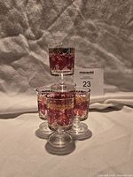 Stacked display of five raspberry-motif aperitif glasses showing design and size