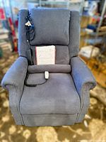 Front view of blue Mega Motion powered lift recliner with wired remote and manual displayed on seat