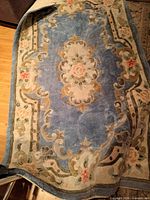 Full view of blue oriental-style rug showing floral medallion and border