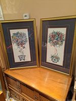 Front view of both framed topiary prints on cabinet