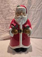 Front view of ceramic Santa Claus cookie jar showing full figure and presents held in hands
