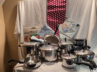 All cookware pieces, chopping mats, apron, towel sets and butter melter grouped together