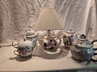 Group shot of teapot lamp and four tea-for-one sets