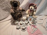 Overall lot showing two teddy bears on doll chairs with complete bunny motif tea set laid out