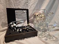 Full lot view with corkscrew kit open, four glasses, metal basket containing napkins
