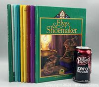 Front view of eight standing hardcover books with Dr Pepper can for scale