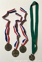 Front view of three Esso medals on tricolour ribbons and torch medal on green ribbon