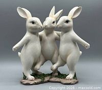 Front view of resin sculpture showing three rabbits linked arm-in-arm