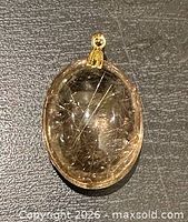 Front view of golden rutilated quartz pendant showing inclusions and bail