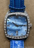 front view showing blue dial, crystal bezel, brand name