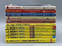 Stack of all 11 Nancy Drew books showing spines with titles and publishers
