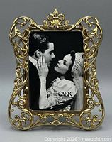 Front view showing ornate gold scrollwork frame and sample photo