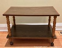 Full view of two-tier table showing spindles and casters