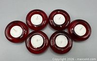 Top view of six red glass candle holders each containing a white tealight candle