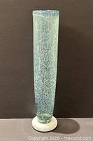 Full frontal view of tall mottled blue glass vase on white base