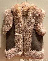 Front view of brown suede shearling vest hanging on hanger