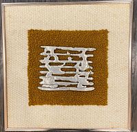 Front view of framed sculpture showing metal relief on textile and frame