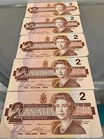 Five obverse sides of Canadian $2 bills showing Queen Elizabeth II portrait and serial prefixes