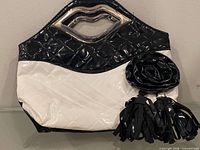 Front view showing two-tone quilted body, metal lip-shaped handles, rosette and tassel